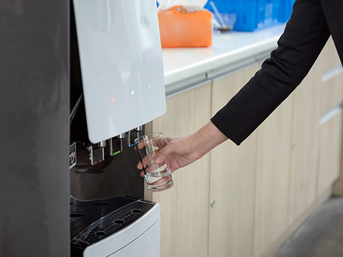 woman filling glass from bottleless water cooler
